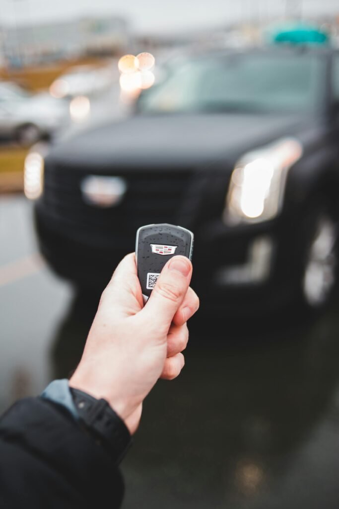 Blurred SUV background with person holding a car key, outdoor setting.